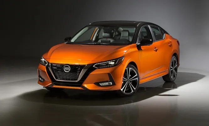 "Nissan Sentra 2020 arancione in uno studio fotografico, illuminata da luci soffuse."